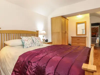a bedroom with a large bed with a wooden headboard at Coombe Cottage in Borrowdale Valley