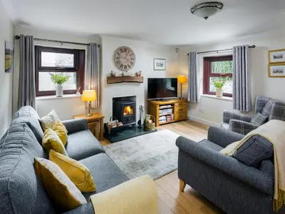 a living room with a couch and a fireplace at Ellwood House in Caldbeck