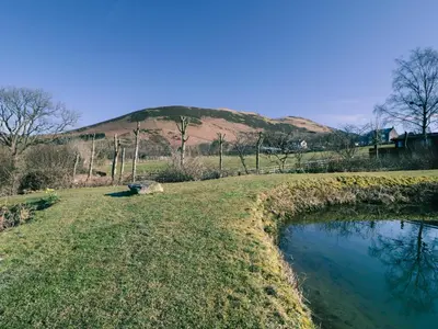 a field with a pool of water in front of a hill at Scales Cottage in Lorton
