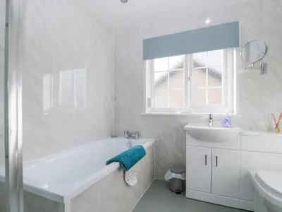 a white bathroom with a tub and a sink at Fountain Cottage in Keswick
