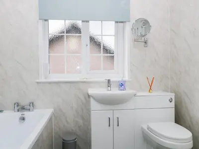 a bathroom with a toilet and a sink and a window at Fountain Cottage in Keswick