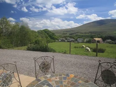 two metal chairs and sheep grazing in a field at Eribel Cottage in Threlkeld
