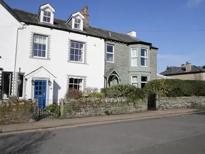 a white house with a blue door on a street at White House in Keswick