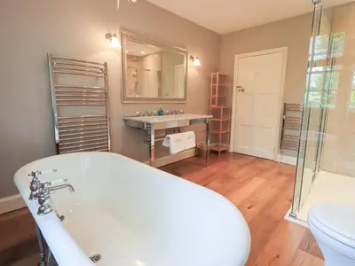 a bathroom with a tub and a sink and a mirror at Little Ellers in Portinscale