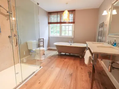 a bathroom with a tub and a shower and a sink at Little Ellers in Portinscale
