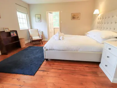 a bedroom with a large white bed and a chair at Little Ellers in Portinscale