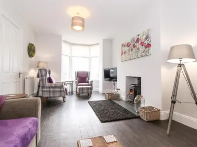 a living room with a couch and chairs and a tv at Latrigg House in Keswick