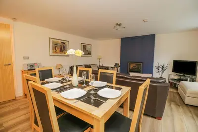 a dining room with a table and chairs and a couch at Derwentwater Apartment in Keswick