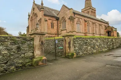 an old stone fence in front of a church at Derwentwater Apartment in Keswick