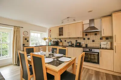 a kitchen with a dining room table and chairs at Derwentwater Apartment in Keswick