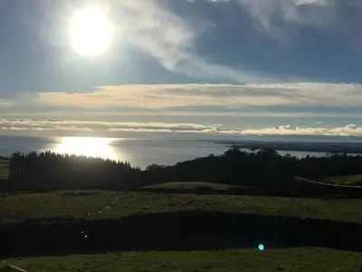 a view of the sun shining over the water at Garden Cottage in Carsluith