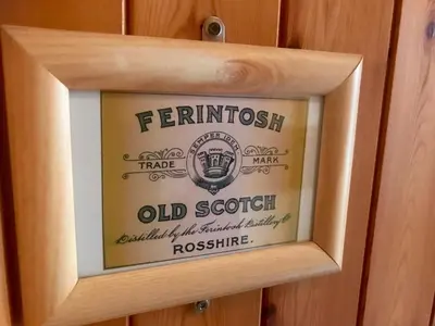 a framed picture of an old scottishouse on a wood wall at Ferintosh Guest House in Dumfries