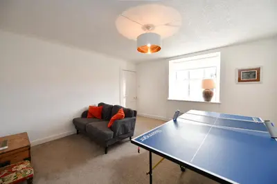 a living room with a ping pong table and a couch at Longhill Farmhouse in Whithorn
