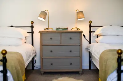 a bedroom with two beds and a dresser with two lamps at Longhill Farmhouse in Whithorn