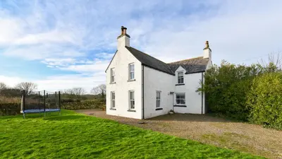 a white house with a basketball hoop in a yard at Longhill Farmhouse in Whithorn