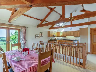 a dining room with a table and a kitchen at New Park Farm - Church Cottage in Ireby
