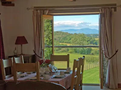 a dining room with a table and a large window at New Park Farm - Church Cottage in Ireby