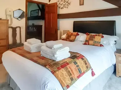 a bedroom with a large bed with towels on it at Woodpecker Cottage in Westward