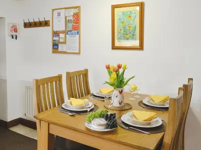 a wooden table with chairs and a dining room at Woodpecker Cottage in Westward