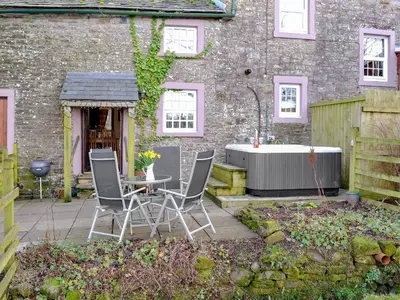 a garden with a table and chairs and a bath tub at Woodpecker Cottage in Westward