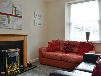 a living room with a red couch and a fireplace at Walla Crag in Keswick