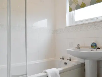 a white bathroom with a sink and a bath tub at Philip's Cottage in Keswick
