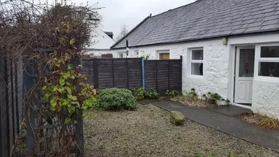 a white house with a black fence and a yard at Silver Ridge, 2 House O` Hill in Newton Stewart