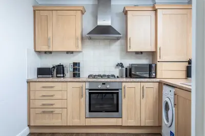 a kitchen with wooden cabinets and a stove top oven at Carrick Retreat - Donnini Apartments in Ayr
