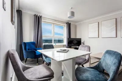 a living room with a table and chairs at Carrick Retreat - Donnini Apartments in Ayr
