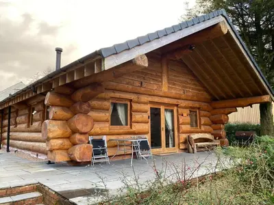 a log cabin with a large pile of logs at Ewes Water Log Cabins in Langholm