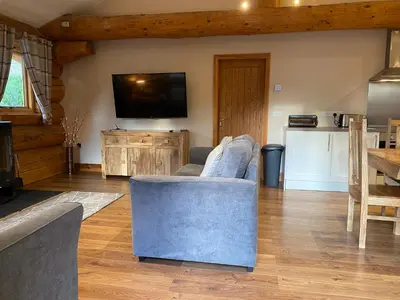 a living room with a couch and a tv at Ewes Water Log Cabins in Langholm