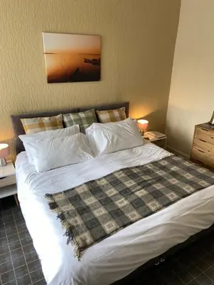 a bedroom with a large bed with white sheets and pillows at No 4 Portpatrick B&B in Portpatrick