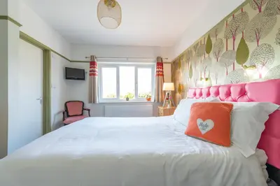 a bedroom with a white bed with a pink headboard at Rickerby Grange in Keswick