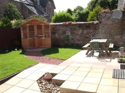 a garden with a bench and a wooden shed at Dairy Cottage in Ayr
