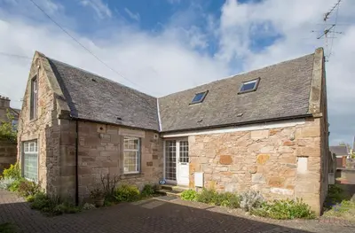 an old stone building with a gray roof at Dairy Cottage in Ayr