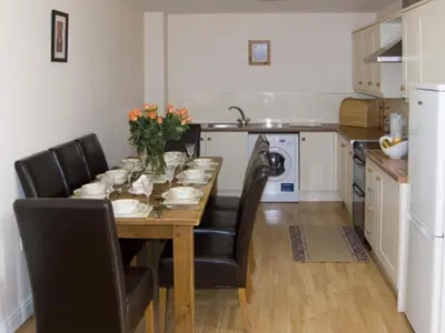 a kitchen with a wooden table with chairs and a dining room at The Loft in Annan