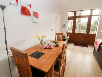 a dining room with a wooden table and chairs at Woodpecker in Ivegill