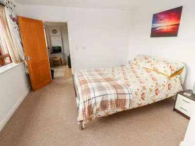 a bedroom with a bed with a blanket and a door at Woodpecker in Ivegill