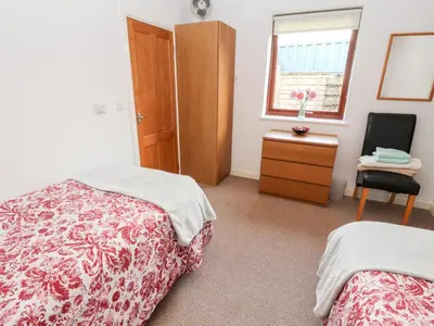 a bedroom with two beds and a chair and a window at Woodpecker in Ivegill