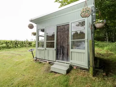 a small shed with a door and windows in a field at Rose Cottage in Stranraer
