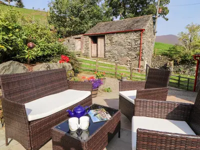a patio with two wicker chairs and a table at The Hayloft in Keswick