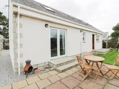 a patio with a table and chairs in front of a house at The Bothy in Mainsriddle