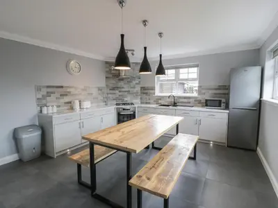 a kitchen with a wooden table and a wooden bench at The Bothy in Mainsriddle