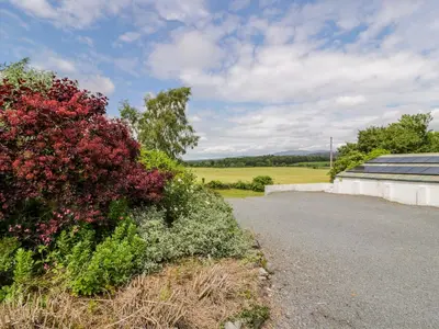 a road next to a house with flowers and a building at The Byre in Newton Stewart