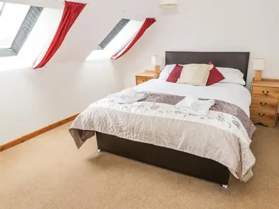 a bedroom with a bed in a room with windows at The Byre in Newton Stewart