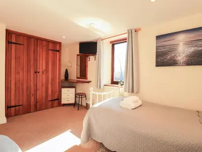 a bedroom with a white bed and a window at Hayloft Cottage in Wigton