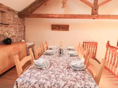 a dining room with a table with plates and dishes at Hayloft Cottage in Wigton