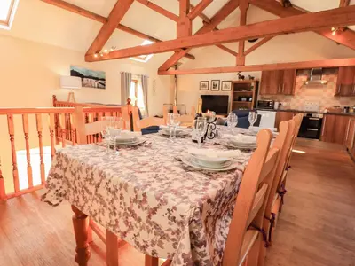 a dining room with a table and a kitchen at Hayloft Cottage in Wigton
