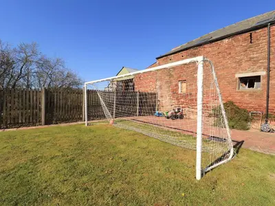 a soccer net in a yard next to a brick building at Hayloft Cottage in Wigton