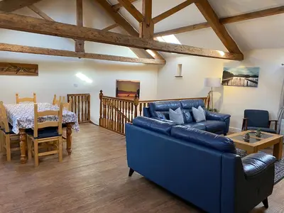 a living room with a blue couch and a table at Hayloft Cottage in Wigton